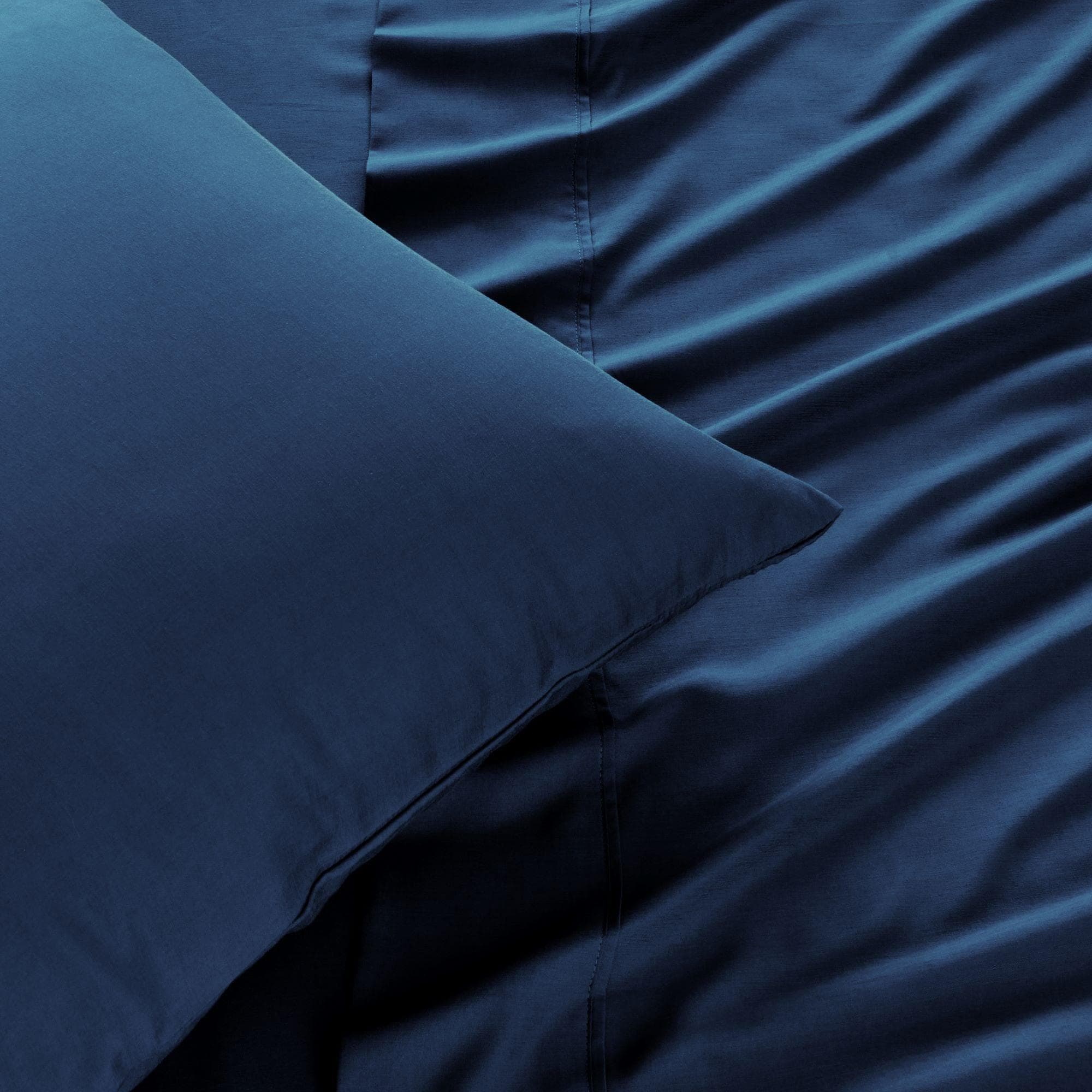 Dark blue luxurious bed sheets and pillowcase, showcasing a soft, smooth texture for a cozy and stylish bedroom setup.